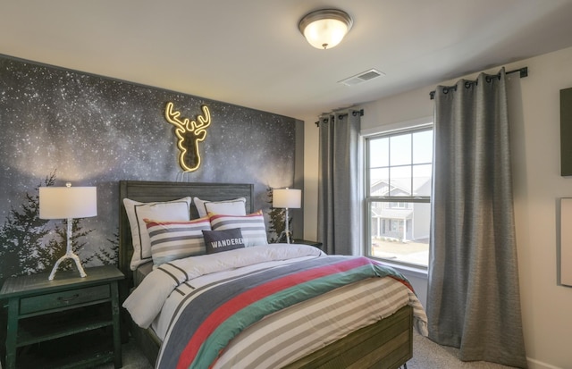 bedroom featuring an accent wall, visible vents, and wallpapered walls