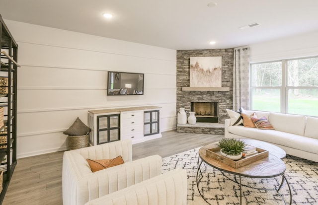 living area with recessed lighting, visible vents, wood finished floors, and a stone fireplace