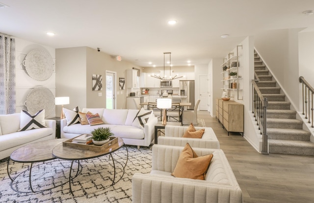 living area with a chandelier, light wood-type flooring, recessed lighting, and stairs