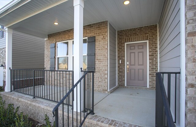 entrance to property with a porch and brick siding