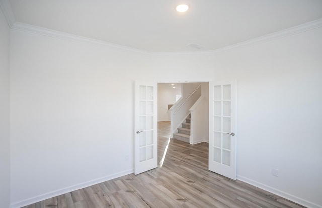 spare room with french doors, crown molding, baseboards, and wood finished floors