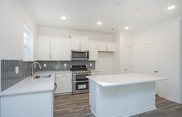 kitchen with appliances with stainless steel finishes, white cabinets, a sink, and ornamental molding