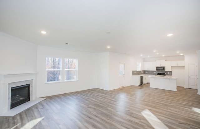 unfurnished living room with light wood finished floors, a premium fireplace, and recessed lighting