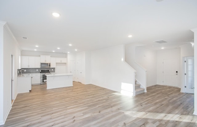 interior space with light wood finished floors, appliances with stainless steel finishes, open floor plan, and a sink