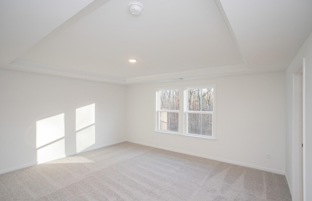 empty room with baseboards, recessed lighting, a raised ceiling, and light colored carpet