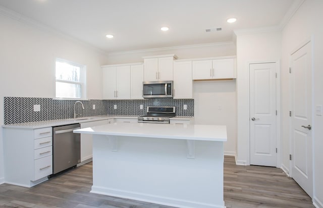 kitchen with visible vents, white cabinets, a kitchen island, appliances with stainless steel finishes, and light countertops