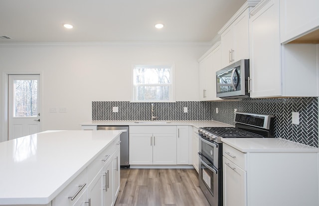 kitchen with tasteful backsplash, appliances with stainless steel finishes, light countertops, crown molding, and a sink