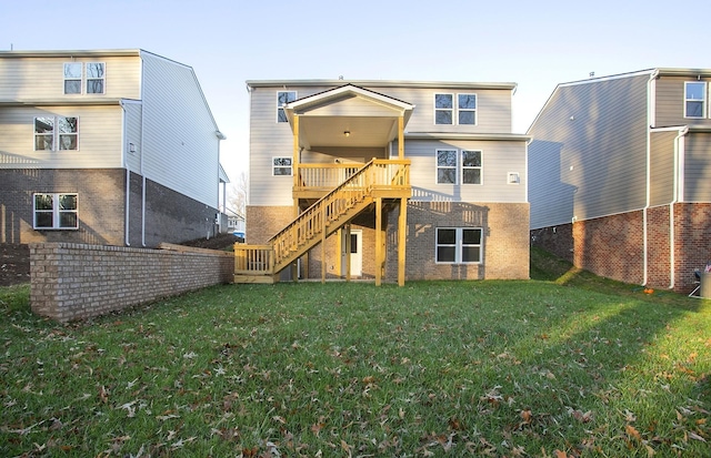 back of property with stairs, a yard, brick siding, and a deck