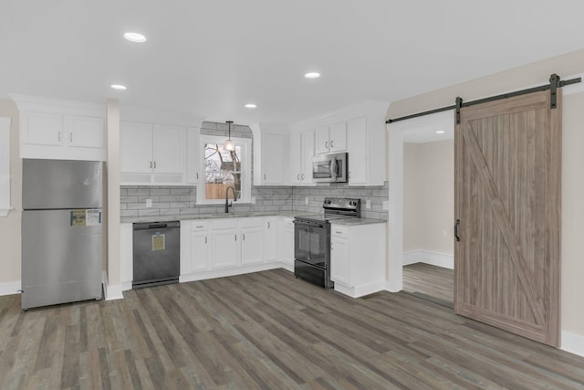 kitchen featuring black appliances, a barn door, and decorative backsplash