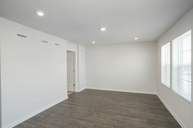 empty room with dark wood-style flooring, recessed lighting, visible vents, and baseboards