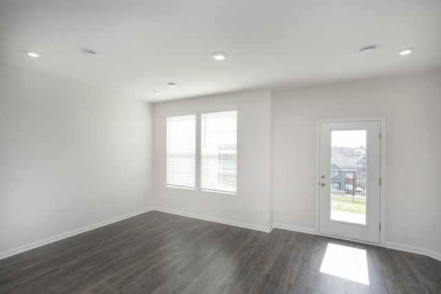 empty room featuring dark wood-style flooring, plenty of natural light, and baseboards