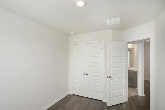 unfurnished bedroom with dark wood-type flooring, a closet, visible vents, and baseboards