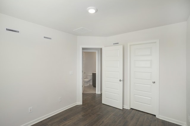 unfurnished bedroom with dark wood-style floors, baseboards, and visible vents