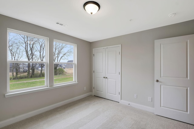 unfurnished bedroom featuring a closet, light carpet, visible vents, and baseboards