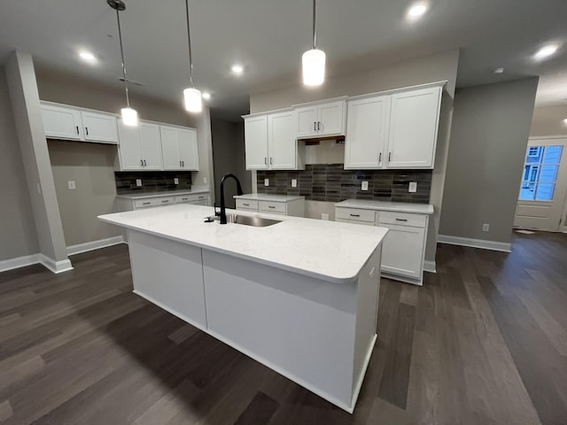 kitchen featuring a kitchen island with sink, white cabinetry, decorative backsplash, and a sink