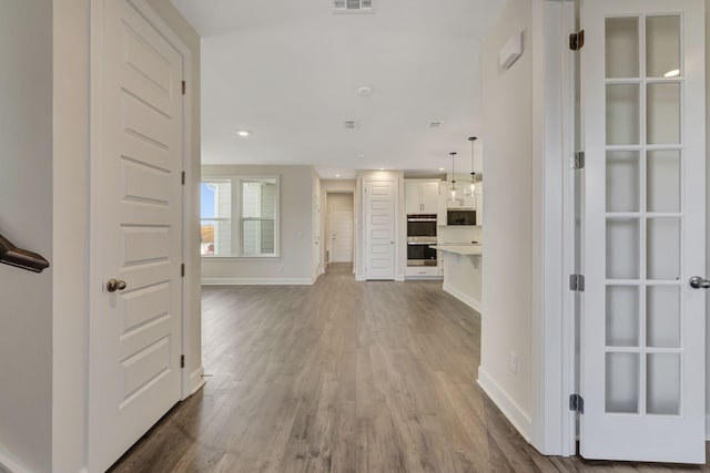 corridor featuring visible vents, recessed lighting, baseboards, and wood finished floors