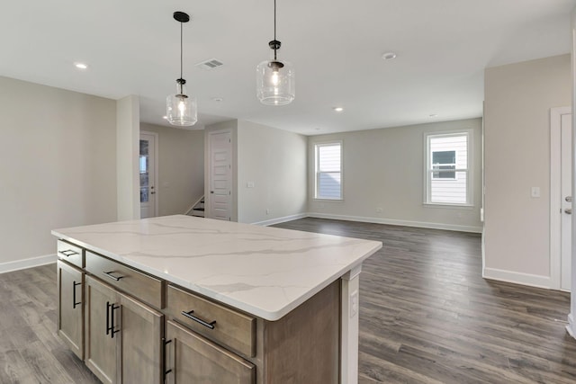 kitchen featuring visible vents, a kitchen island, dark wood-style floors, baseboards, and hanging light fixtures