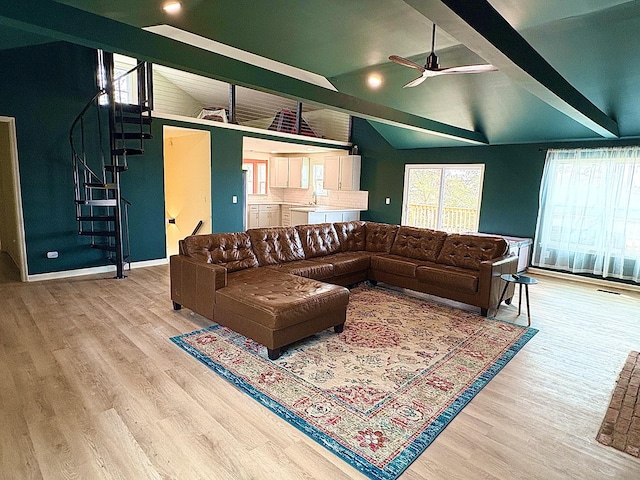 living area with beam ceiling, ceiling fan, stairway, and wood finished floors