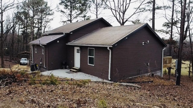 view of side of home with entry steps, a patio area, and metal roof