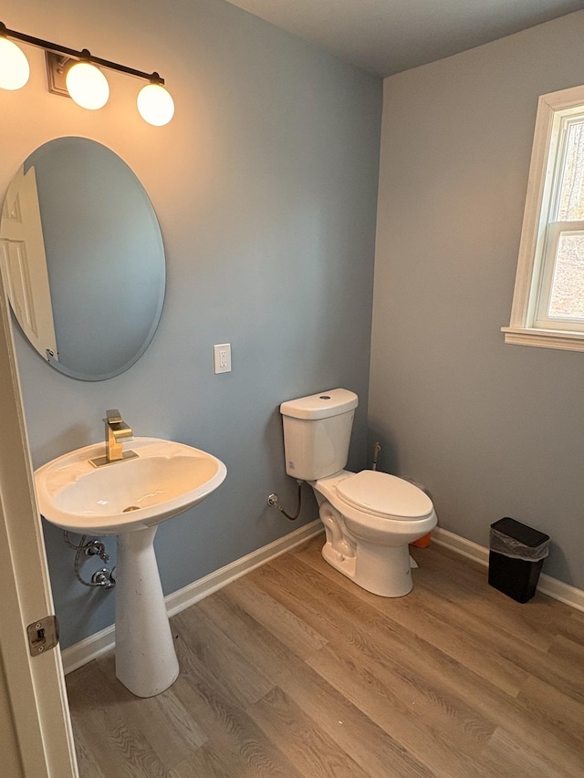 bathroom with toilet, baseboards, and wood finished floors