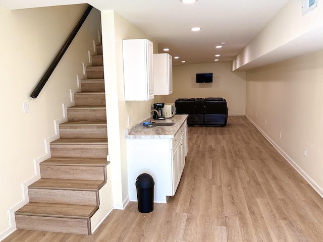 kitchen featuring light wood finished floors, recessed lighting, visible vents, white cabinetry, and a sink