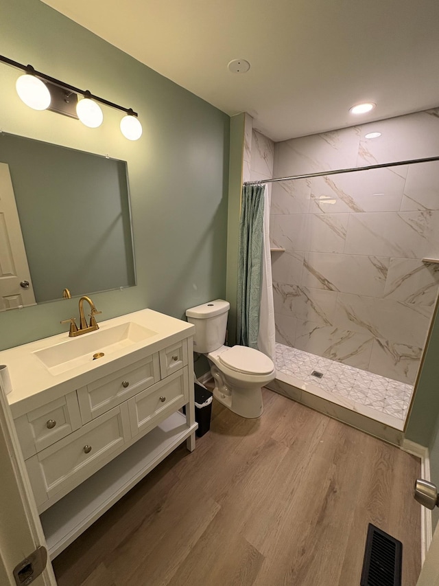 bathroom with a stall shower, visible vents, toilet, wood finished floors, and vanity