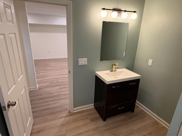 bathroom with baseboards, wood finished floors, and vanity