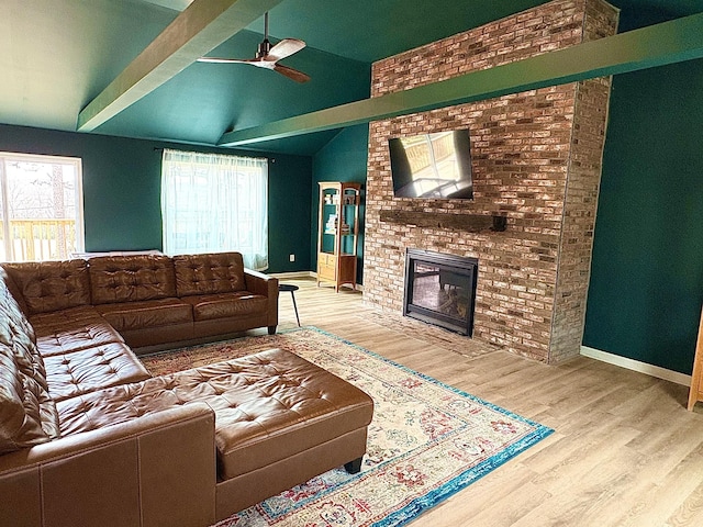 living area with vaulted ceiling, a fireplace, baseboards, and wood finished floors