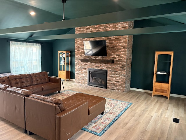 living area with lofted ceiling with beams, a brick fireplace, baseboards, and wood finished floors