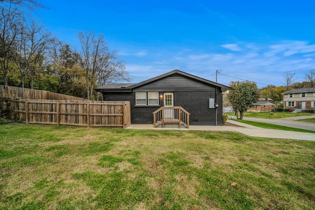 rear view of property featuring brick siding, crawl space, fence, and a lawn