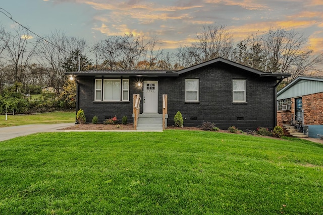 view of front facade featuring crawl space, brick siding, and a yard