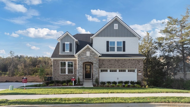 craftsman-style house with a garage, a shingled roof, a front lawn, and brick siding