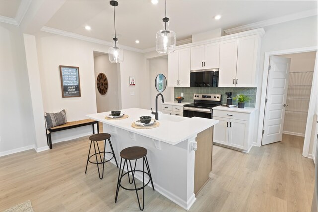 kitchen featuring a breakfast bar area, light wood finished floors, backsplash, stainless steel range with electric cooktop, and an island with sink