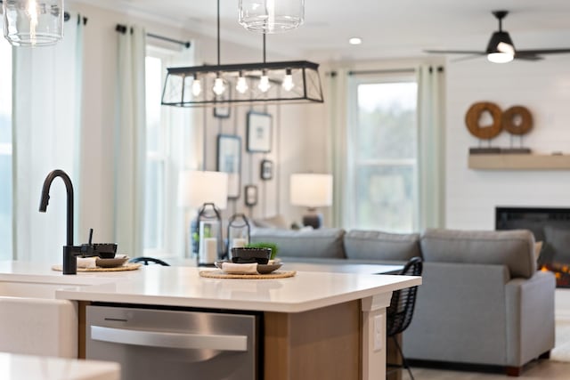 kitchen with a glass covered fireplace, open floor plan, stainless steel dishwasher, and light countertops