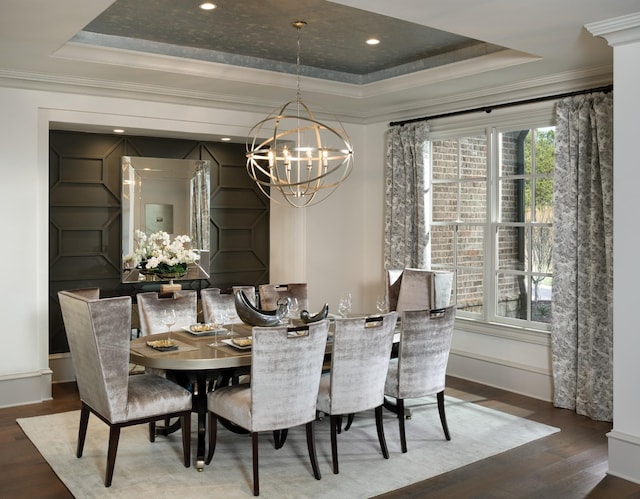 dining space featuring a chandelier, a raised ceiling, crown molding, and wood finished floors