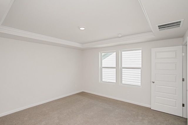 empty room featuring carpet flooring, visible vents, baseboards, ornamental molding, and a tray ceiling