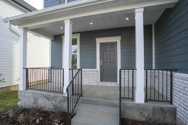 doorway to property featuring a porch and brick siding