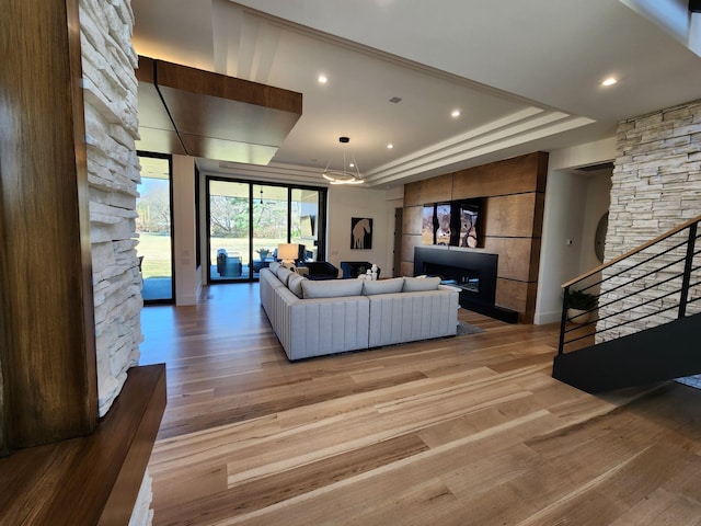 living area featuring light wood finished floors, stairway, and a raised ceiling