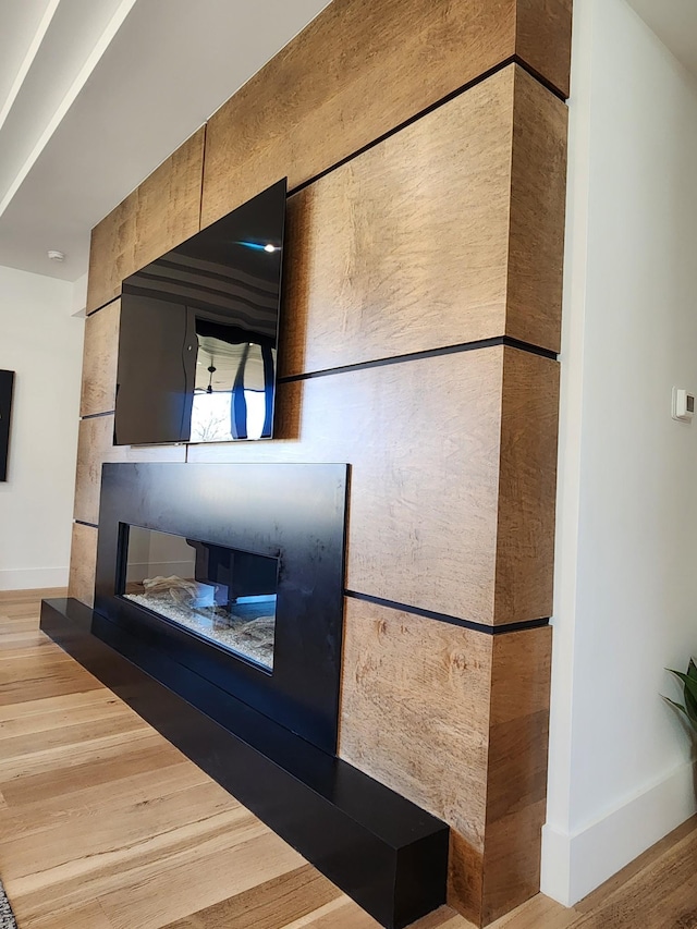 interior details featuring a fireplace, wood finished floors, and baseboards