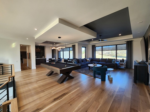 recreation room featuring a wealth of natural light, a tray ceiling, billiards, and light wood-style flooring