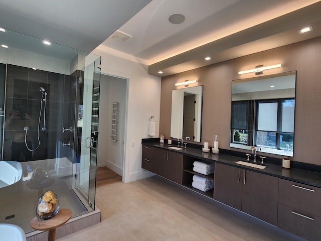 full bathroom with a stall shower, a sink, baseboards, and double vanity