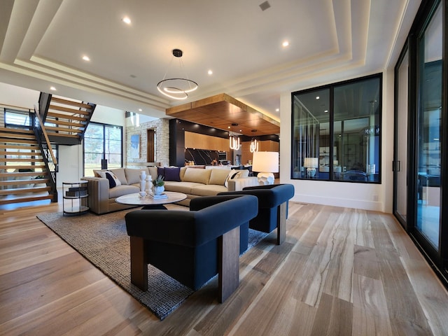 living area with a tray ceiling, stairway, recessed lighting, and wood finished floors