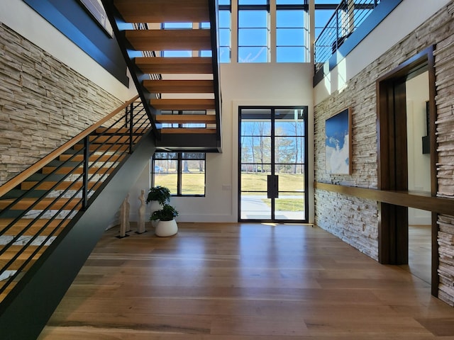 entrance foyer featuring a towering ceiling, stairway, and wood finished floors