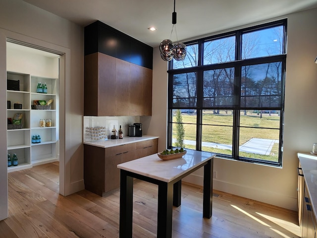 kitchen featuring modern cabinets, light countertops, light wood finished floors, and an inviting chandelier