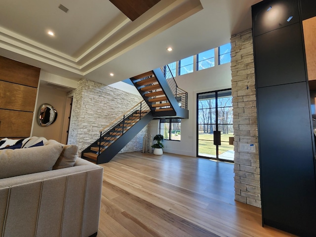 living area featuring a raised ceiling, stairway, and wood finished floors