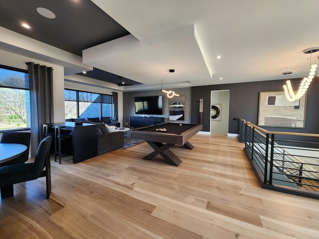 rec room with a tray ceiling, recessed lighting, light wood-style floors, a chandelier, and billiards