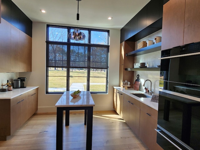 kitchen featuring open shelves, light wood-type flooring, a sink, and light countertops