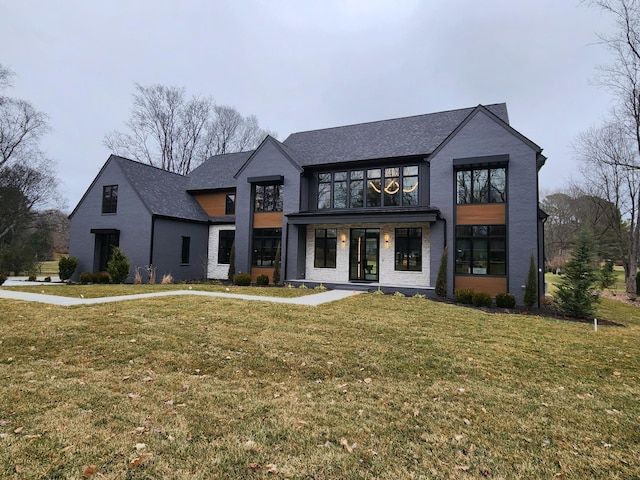 view of front of house with brick siding, french doors, and a front yard