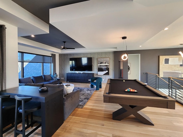 recreation room featuring light wood finished floors, billiards, ceiling fan, a tray ceiling, and recessed lighting