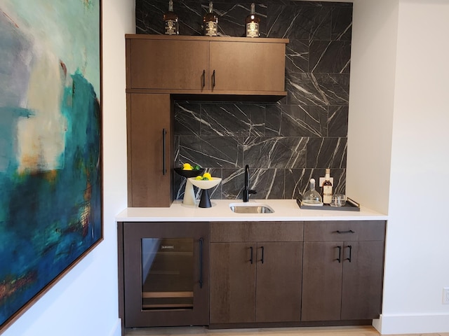 bar featuring wine cooler, backsplash, and a sink